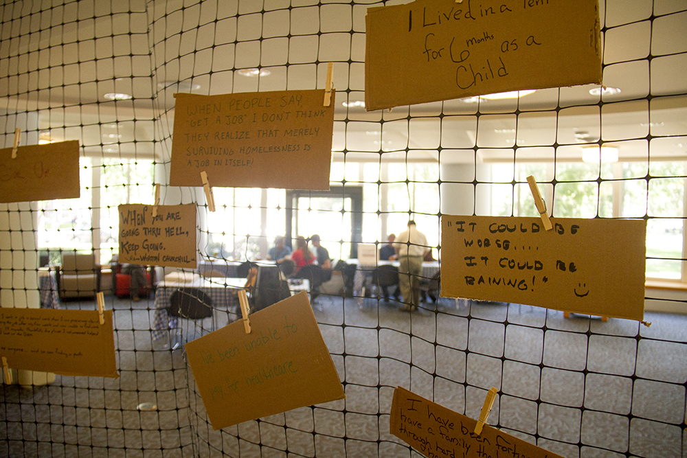Cardboard signs hang in the Denver Public Library during a day of empathy-fueled events meant to teach people about what it's like to be homeless. (Kevin J. Beaty/Denverite)
