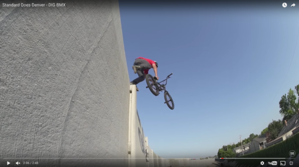 A BMX rider launches off a highway wall near Denver in this YouTube screenshot. (YouTube/Standard Byke)