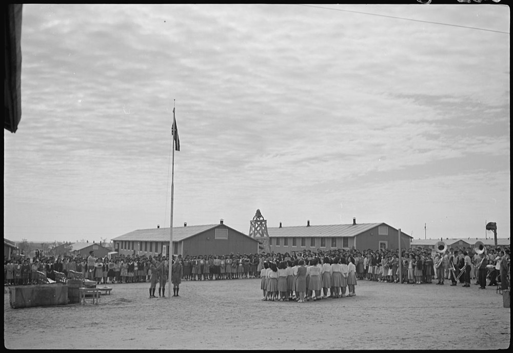 The U.S. flag is raised at a high school ceremony in the Granada Relocation Center, a concentration camp for people of Japanese descent, in Amache, Colorado. (Joe McClelland/National Archives and REcords Administration)