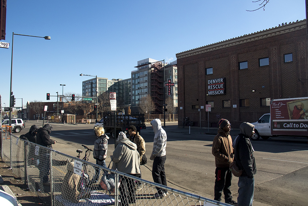 People stand across the street from the Denver Rescue Mission. (Kevin J. Beaty/Denverite)