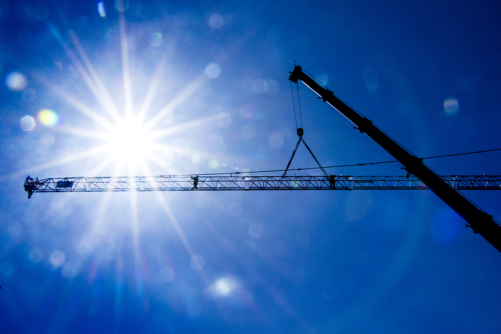 Compass Equipment workers construct a tower crane on a jobsite on Pearl Street at 16th Avenue, April 15, 2018. (Kevin J. Beaty/Denverite)