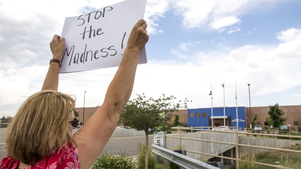 Becky Keiter holds a sign outside of the GEO private immigrant detention facility in Aurora as protesters spoke out against child separations in immigration cases, June 14, 2018. (Kevin J. Beaty/Denverite)