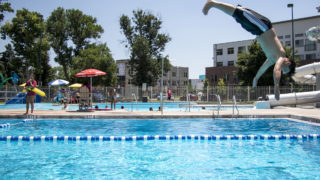 Lifeguard Marina Luna keeps an eagle eye over the pool as Anthem, who is 14, takes a dive. The La Alma Recreation Center, July 11, 2018. (Kevin J. Beaty/Denverite)