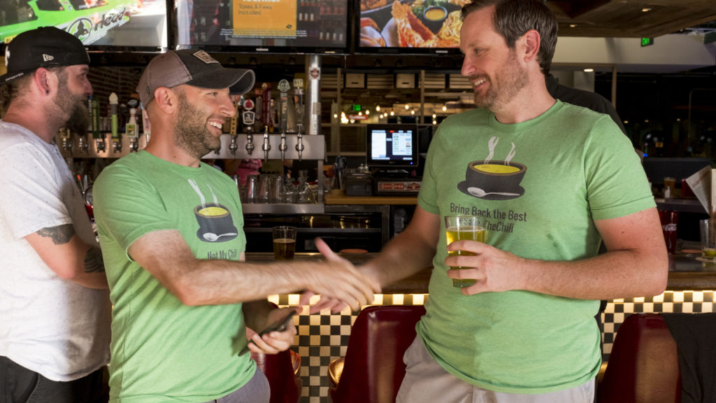 Chris Lombardi (left) and Rob Toftness shake hands after winning, sort of, the Cherry Cricket's chile cookoff, July 19, 2018. (Kevin J. Beaty/Denverite)
