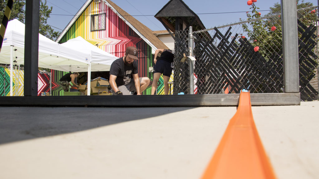 Brian Colonna sets up Hot Wheels car tracks around "This Machine Has A Soul," an art installation by Warm Cookies of the Revolution meant to get people thinking about participatory budgeting, Aug. 15, 2018. (Kevin J. Beaty/Denverite)