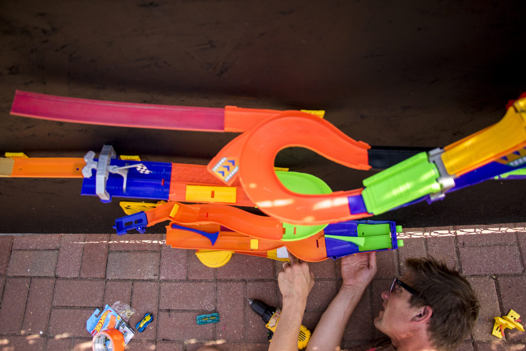 Erik Edborg sets up a Hot Wheels track. Warm Cookies of the Revolution puts the finishing touches on "This Machine Has A Soul," an art installation meant to get people thinking about participatory budgeting, Aug. 15, 2018. (Kevin J. Beaty/Denverite)