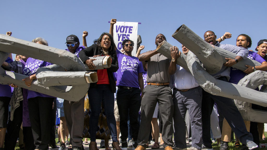 Activists break the chains of a giant pair of shackles after a rally to vote "yes" on Amendment A, to make slavery unconstitutional in Colorado, at City Park, Aug. 28, 2018. (Kevin J. Beaty/Denverite)
