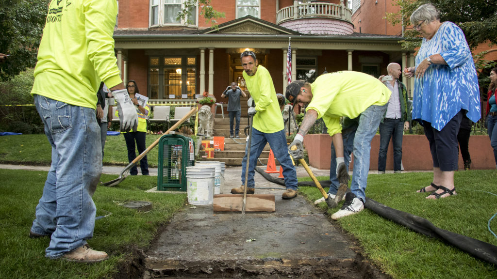 Workers with Ruben Rivera LLC (that's him in the middle) level out flagstone slabs in front of Diane Travis' 126-year-old home in North Capitol Hill. That's Travis on the right watching. Sept. 5, 2018. (Kevin J. Beaty/Denverite)