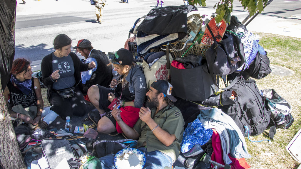 John Cavazos (right) hangs out under a tree by the Denver Public Library, Sept. 26, 2018. (Kevin J. Beaty/Denverite)
