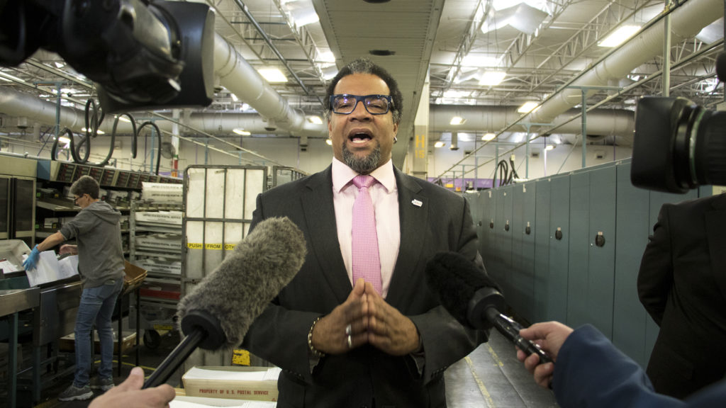 Denver Elections spokesman Alton Dillard speaks to press at the U.S. Postal Service's massive sorting and shipping facility in Stapleton as ballots are shipped out to voters, Oct. 16, 2018. (Kevin J. Beaty/Denverite)