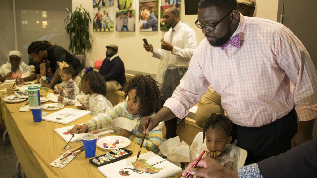 Ryan Ross (right) paints as his daughter, Zoe (3), enjoys a cookie. A Father Daughter Occasion at the Dahlia Campus for Health and Well-Being in Northeast Park Hill, Oct. 27, 2018. (Kevin J. Beaty/Denverite)