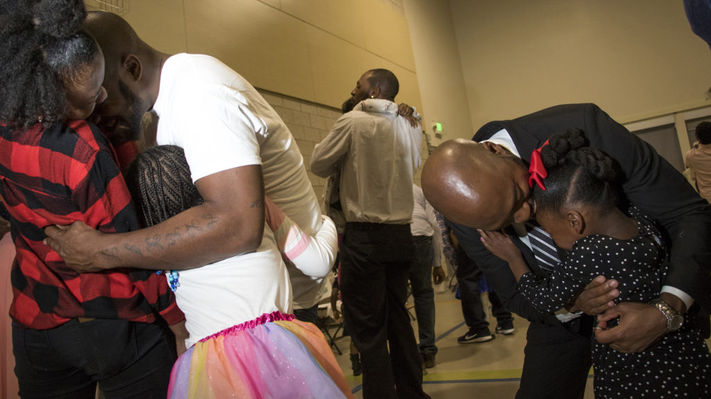 Eric Wedgeworth and his daughters Aryss (6, left to right) and Aniya (13) and Michael Dennis and his daughter, Kaitlyn (5), embrace during A Father Daughter Occasion at the Dahlia Campus for Health and Well-Being in Northeast Park Hill, Oct. 27, 2018. (Kevin J. Beaty/Denverite)