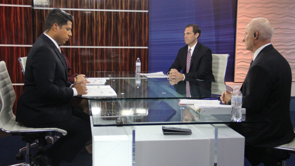 U.S. Rep. Mike Coffman (right) sits next to to Jason Crow (middle) while Univision Colorado Anchor Juan Carlos Gutierrez looks at notes before the start of a debate on Monday, Oct. 22, 2018, in Denver. (Esteban L. Hernandez/Denverite)