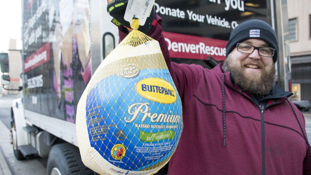 Jeremy Stubbs, food distribution coordinator for the Denver Rescue Mission, holds up the first donation of their holiday turkey drive outside of Republic Plaza, Nov. 2, 2018. (Kevin J. Beaty/Denverite)