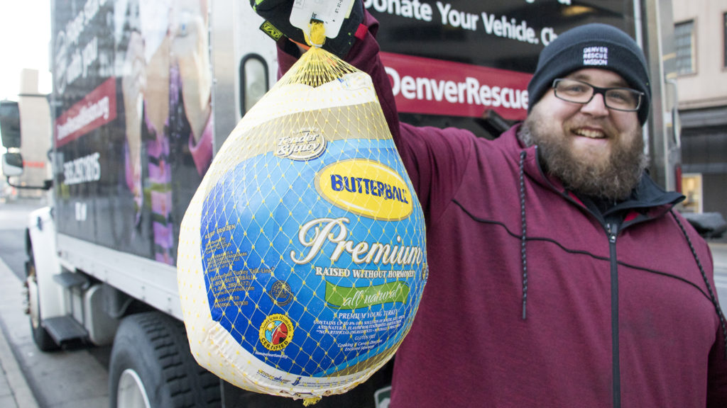 Jeremy Stubbs, food distribution coordinator for the Denver Rescue Mission, holds up the first donation of their holiday turkey drive outside of Republic Plaza, Nov. 2, 2018. (Kevin J. Beaty/Denverite)