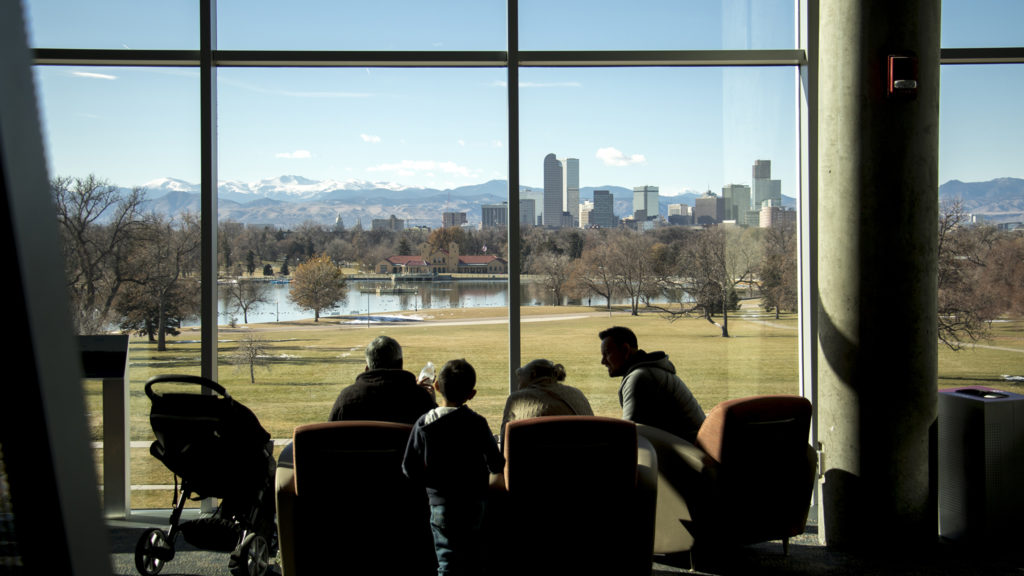 A family sits by a large window at the Denver Museum of Nature and Science, Nov. 26, 2018. (Kevin J. Beaty/Denverite)