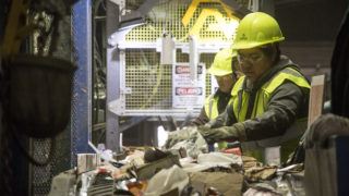 Women pick through a stream of recycled materials inside the Altogether Recycling center in Globeville, Dec. 3, 2018. (Kevin J. Beaty/Denverite)