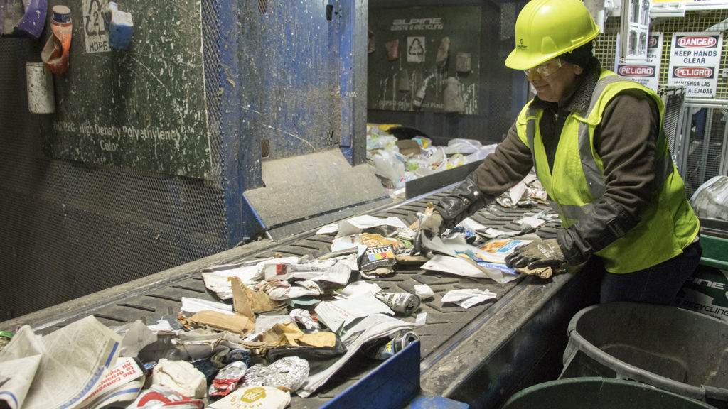 Yuderkarely Campps sorts recycled materials inside the Altogether Recycling center in Globeville, Dec. 3, 2018. (Kevin J. Beaty/Denverite)