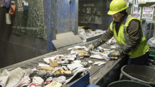 Yuderkarely Campps sorts recycled materials inside the Altogether Recycling center in Globeville, Dec. 3, 2018. (Kevin J. Beaty/Denverite)
