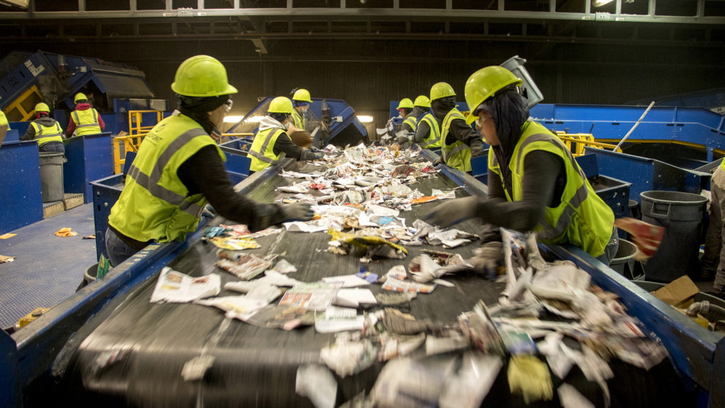 Workers pick through a stream of recycled materials inside the Altogether Recycling center in Globeville, Dec. 3, 2018. (Kevin J. Beaty/Denverite)