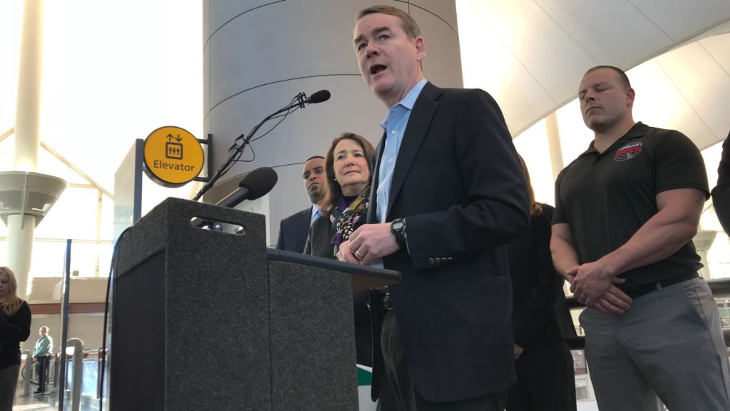 U.S. Sen. Michael Bennet (center) during a press conference on the government shutdown on Monday, Jan. 14, 2019, at DIA. Behind him (from left): U.S. Reps. Joe Neguse and Diana DeGette, and local air traffic union president Joshua Waggener. (Esteban L. Hernandez/Denverite)