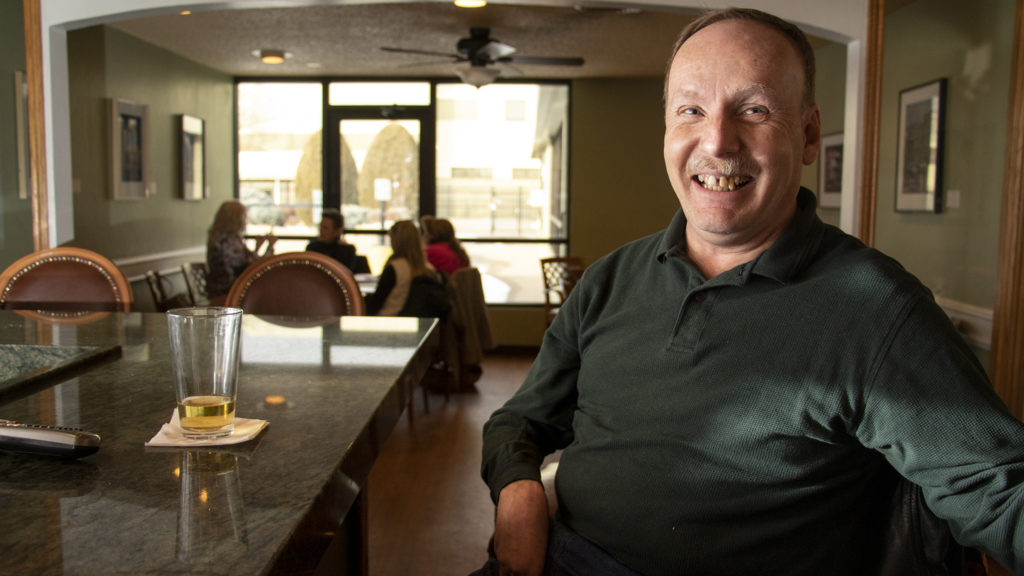 Phil Wampler, who has lived in Windsor Gardens for two and a half years, poses for a portrait at the Blossoms Restaurant bar in the neighborhood's community center. Feb. 27, 2019. (Kevin J. Beaty/Denverite)