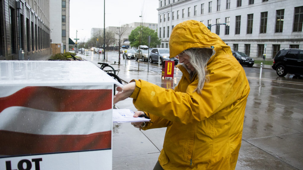Cheryl Specter drops not one, but three ballots outside of the Denver Elections Division on election day, May 7, 2019. (Kevin J. Beaty/Denverite)