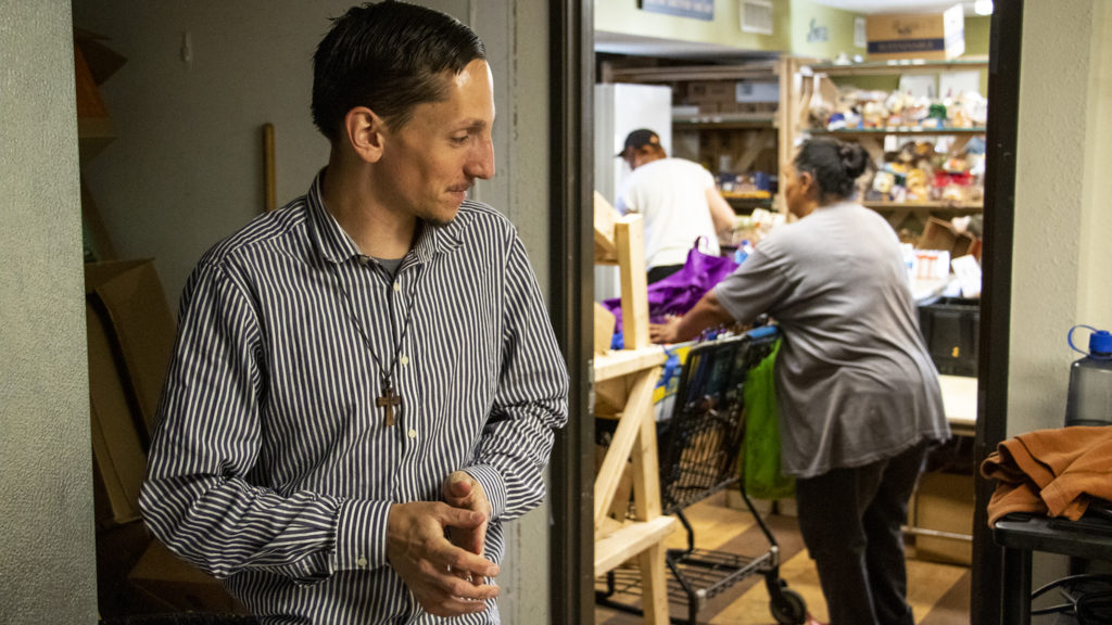 Michael Bruno, who runs Inner City Parish's food pantry, speaks to a reporter in a stockroom. La Alma-Lincoln Park, May 15, 2019. (Kevin J. Beaty/Denverite)