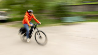 Cyclists speed by Denver Parks and Recreation's safety booth on the Cherry Creek Trail, May 16, 2019. (Kevin J. Beaty/Denverite)