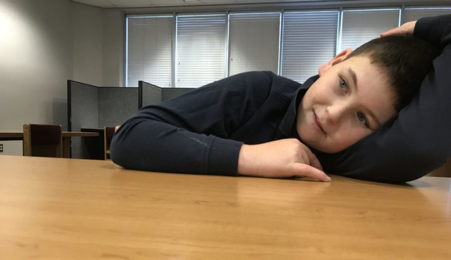 Jake DiProfio rests his head on a table at the local library during a tutoring session. (Melanie Asmar/Chalkbeat)