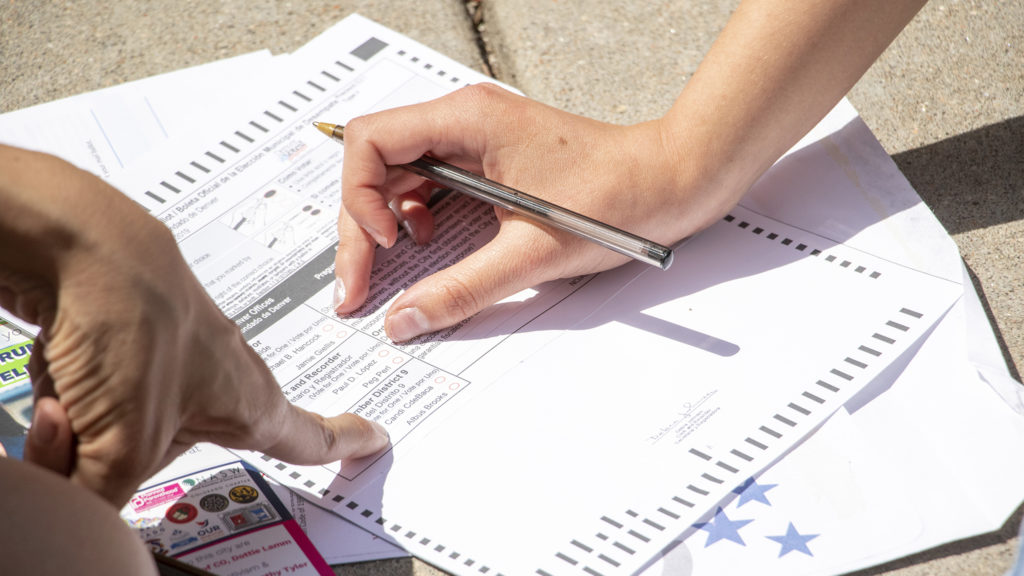 Candi CdeBaca teaches first-time voter MaLinda Medina how to cast a ballot as she canvasses in Five Points on election day, June 4, 2019.