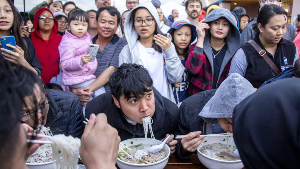 Jack Le struggles to keep up during a pho eating context at the Little Saigon Night Market. Federal Boulevard, June 21, 2019. (Kevin J. Beaty/Denverite)