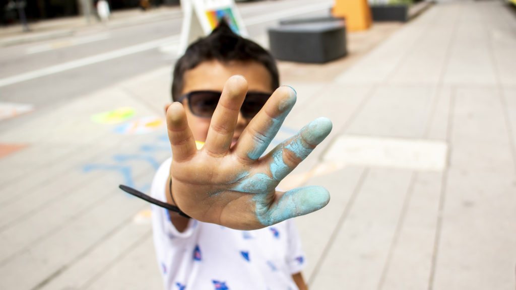 Azariah (5) helped Artist Pat Milbery paint a sidewalk at 14th and Curtis Streets to promote Denver Parks and Recreation's downtown tree canopy expansion, July 17, 2019. (Kevin J. Beaty/Denverite)