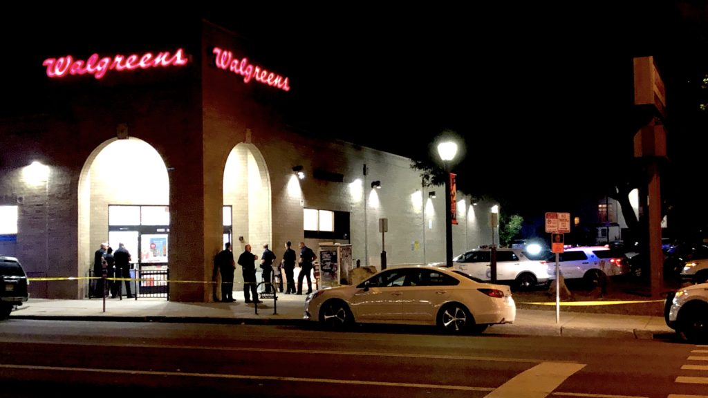 A group of police officers attempt to coax a suspect out of the Walgreens on East Colfax Avenue. (David Sachs/Denverite)