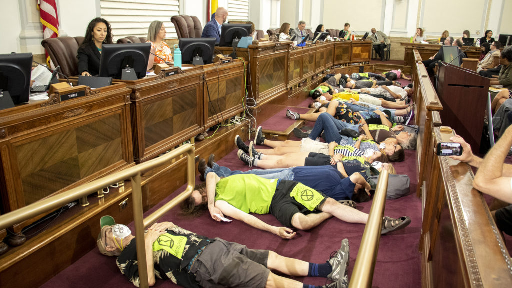 Climate change activists perform a "die-in" during Denver City Council. Aug. 5, 2019. (Kevin J. Beaty/Denverite)