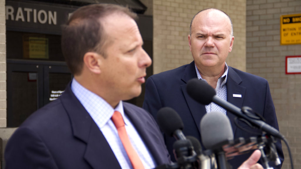 Public Safety Director Troy Riggs (right) looks on while Community Corrections Director Greg Mauro speaks a press conference outside the Police Administration Building on Wednesday, Aug. 21, 2019, in Denver. (Esteban L. Hernandez/Denverite)