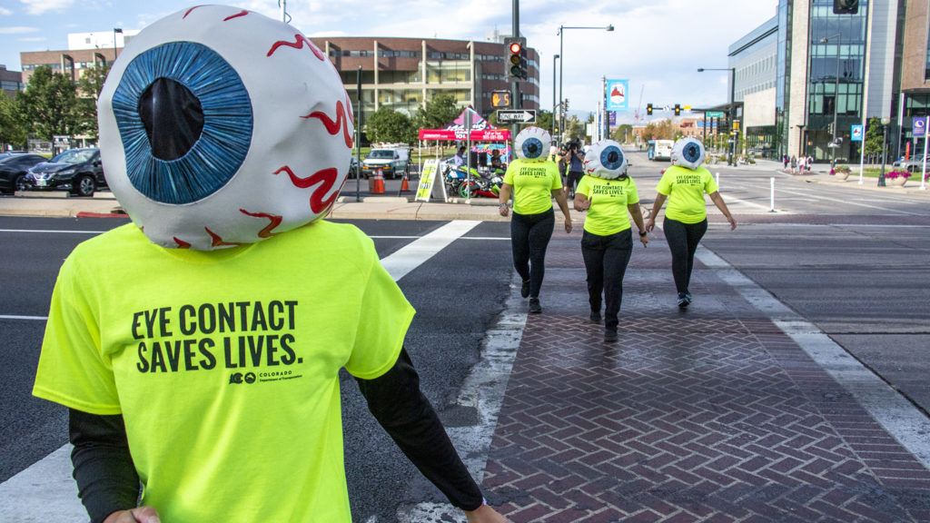 Katie Clements, a CDOT eyeball, crosses Speer Boulevard to promote eye contact awareness, Sept. 4, 2019. (Kevin J. Beaty/Denverite)