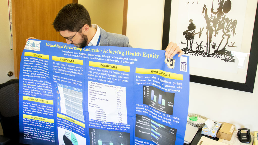 Attorney Marc Scanlon, with Medical Legal Partnership Colorado, shows a poster presentation inside his office at the Salud Family Medical Center in Commerce City, Sept. 10, 2019. (Kevin J. Beaty/Denverite)