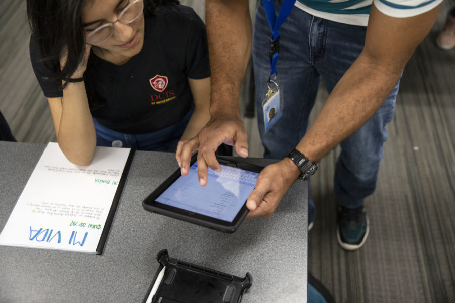 A DCIS Montbello student asks a question to English Language Development teacher Carlos Balanta during a classroom assignment at the Denver, Colo., school. May 2019. (Nathan W. Armes/Chalkbeat)