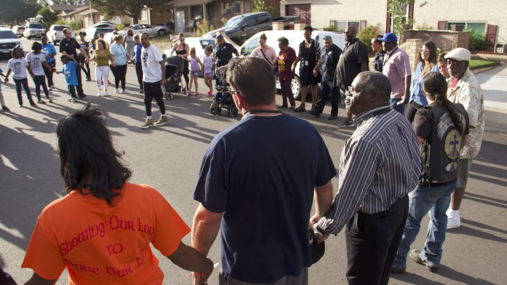 Montbello residents and police hold hands in a prayer circle during a community meeting in Montbello on Wednesday, Sept. 18, 2019, in Denver. (Esteban L. Hernandez/Denverite)