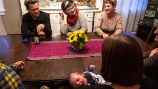 Josiah Hesse (clockwise from top-left), Samantha Hinshaw, Meredith Turk, Stephen Polk, Sarah Wells, baby Charlie Wells-Polk and Sara Baumann sit around their communal table at 901 N. Clarkson St. Oct. 1, 2019. (Kevin J. Beaty/Denverite)