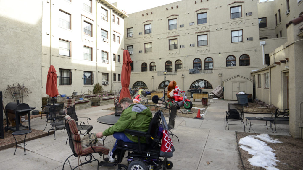 Randy Kilbourn sits with his dog Arlo on the patio of the Olin Hotel Apartments in Capitol Hill. (Lindsay Fendt/Denverite)