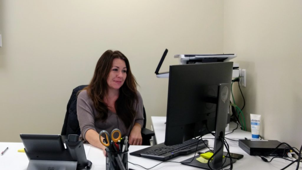Executive assistant April Herrera at the front desk on Dec. 5 of Resource Connect, where families can get help with food, housing and other challenges they might not think of as medical, but which affect health. (Donna Bryson/Denverite)