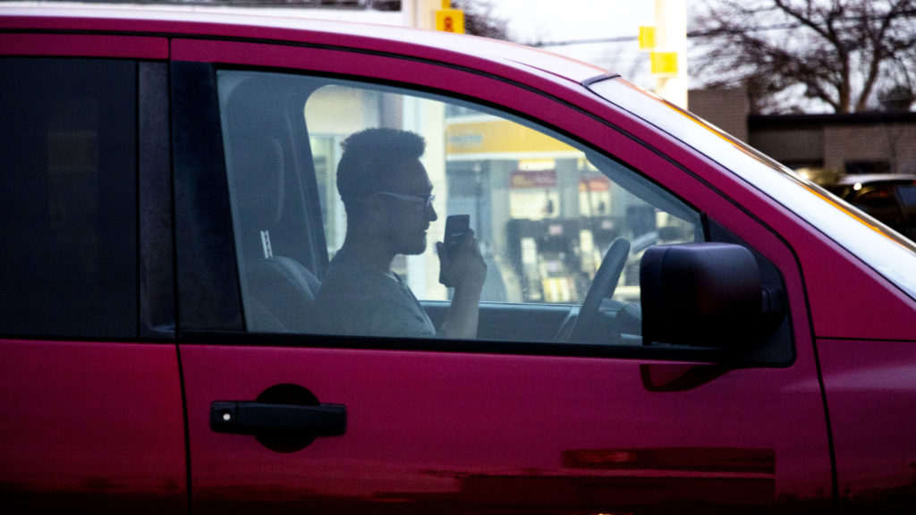 A man talks on a phone in a car at the corner of Federal Boulevard and Florida Avenue, Jan. 16, 2020. (Kevin J. Beaty/Denverite)
