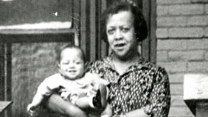Photograph of Doctor Justina L Ford holding a baby while standing on a porch, 2825 High St., circa 1935. (Denver Public Library/Western History Collection)