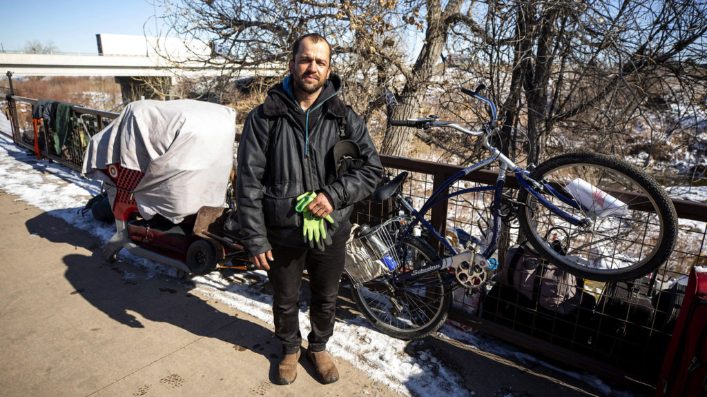 Isaac Finley poses for a portrait with his stuff, which he packed up after Denver officials warned he would be ticketed or arrested if he stayed camped here along the Sand Creek, right on the line between Denver and Commerce City. Feb. 5, 2020. (Kevin J. Beaty/Denverite)