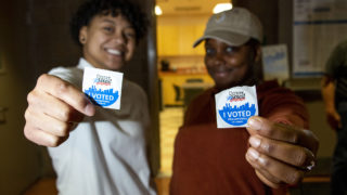 Elizabeth Ngirailab and Bria Daniel pose for a portrait with their stickers on Super Tuesday at the Hiawatha Davis recreation center in Northeast Park Hill, March 3, 2020. (Kevin J. Beaty/Denverite)