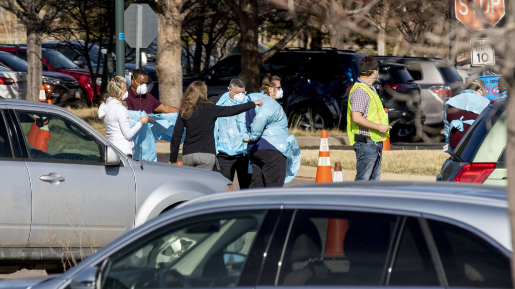 Workers don scrubs as people line up in cars for testing at the Colorado Department of Health and Environment's COVID-19 testing station in Lowry. March 11, 2020. (Kevin J. Beaty/Denverite)