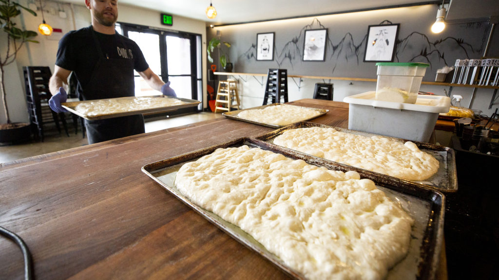 Alex Figura, co-owner of Dio Mio, prepares bread for takeout orders. Five Points, March 20, 2020. (Kevin J. Beaty/Denverite)