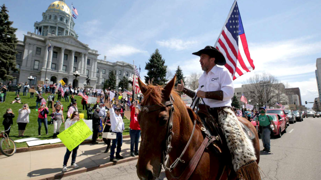 Couy Griffin rides a horse up Lincoln Street as protesters demand the end to Colorado's stay-at-home order at the state Capitol building. April 19, 2020. (Kevin J. Beaty/Denverite)